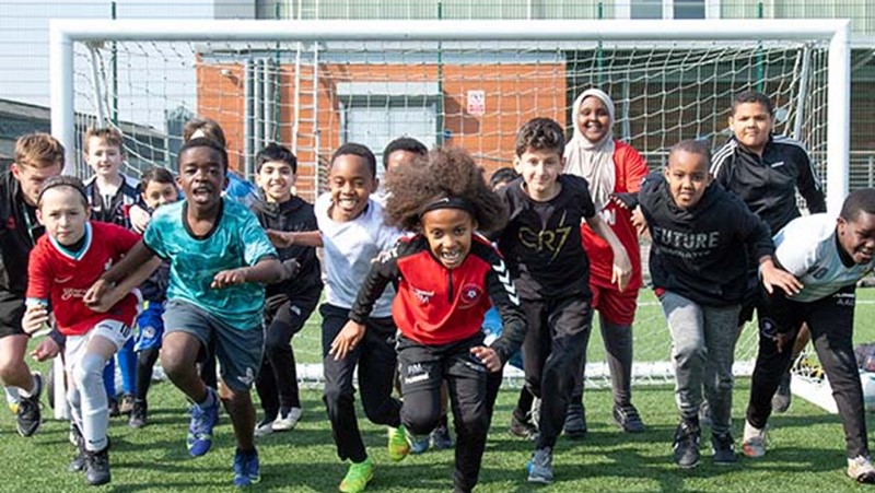 group of sporty children about to run forwards. Goalpost in background